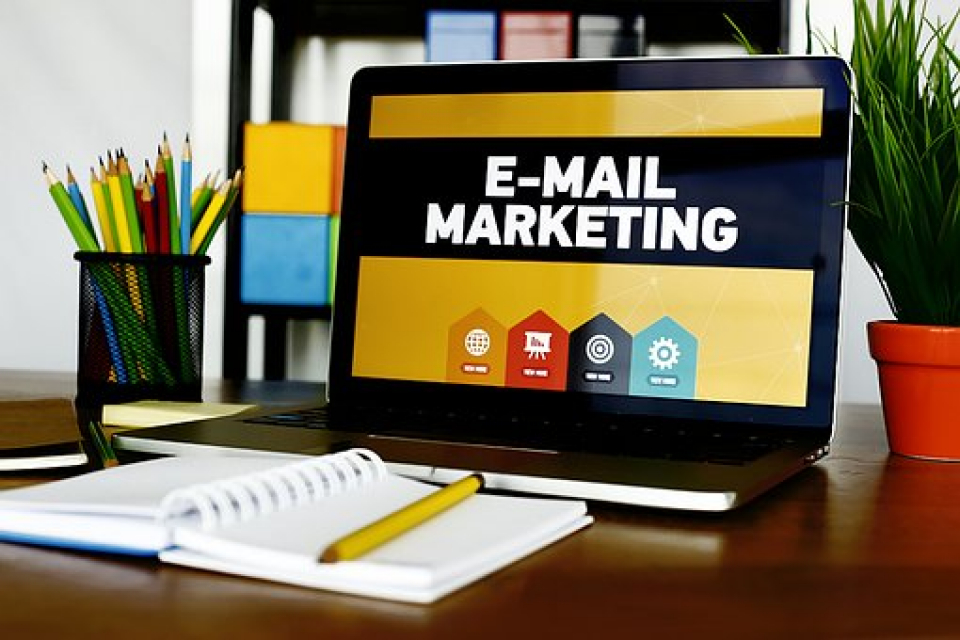 Computer con una sfondo contenente diverse icone di strumenti e tool di email marketing